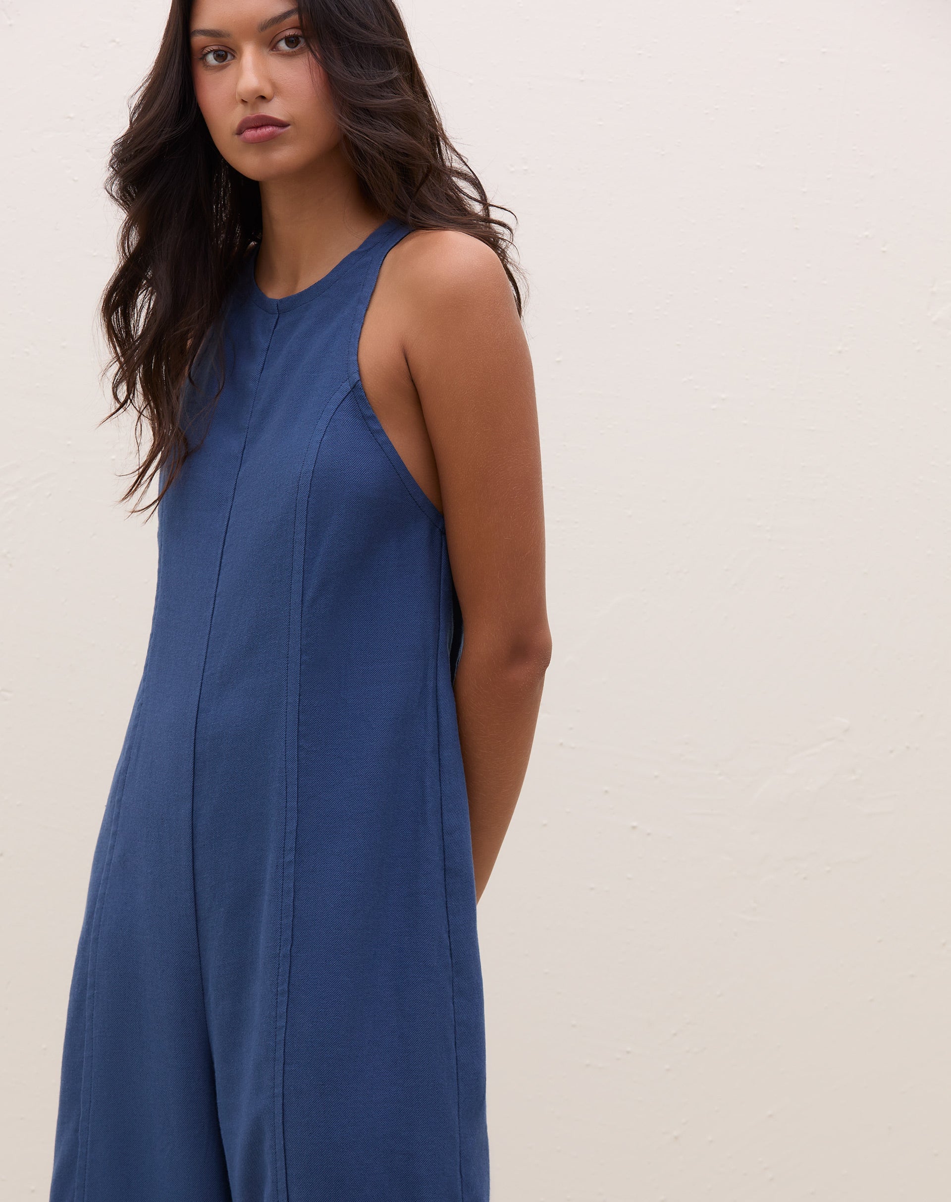 Vista lateral do macacão azul mostrando o ajuste na cintura.