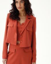 Blazer cropped marrom com bolsos e lapela entalhada, visto de frente.