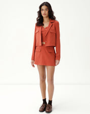 Modelo vestindo blazer cropped marrom com shorts combinando, vista completa.