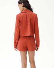 Modelo vestindo blazer cropped marrom com shorts combinando, vista traseira.