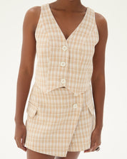 Close-up do colete de alfaiataria com estampa xadrez e decote em V.