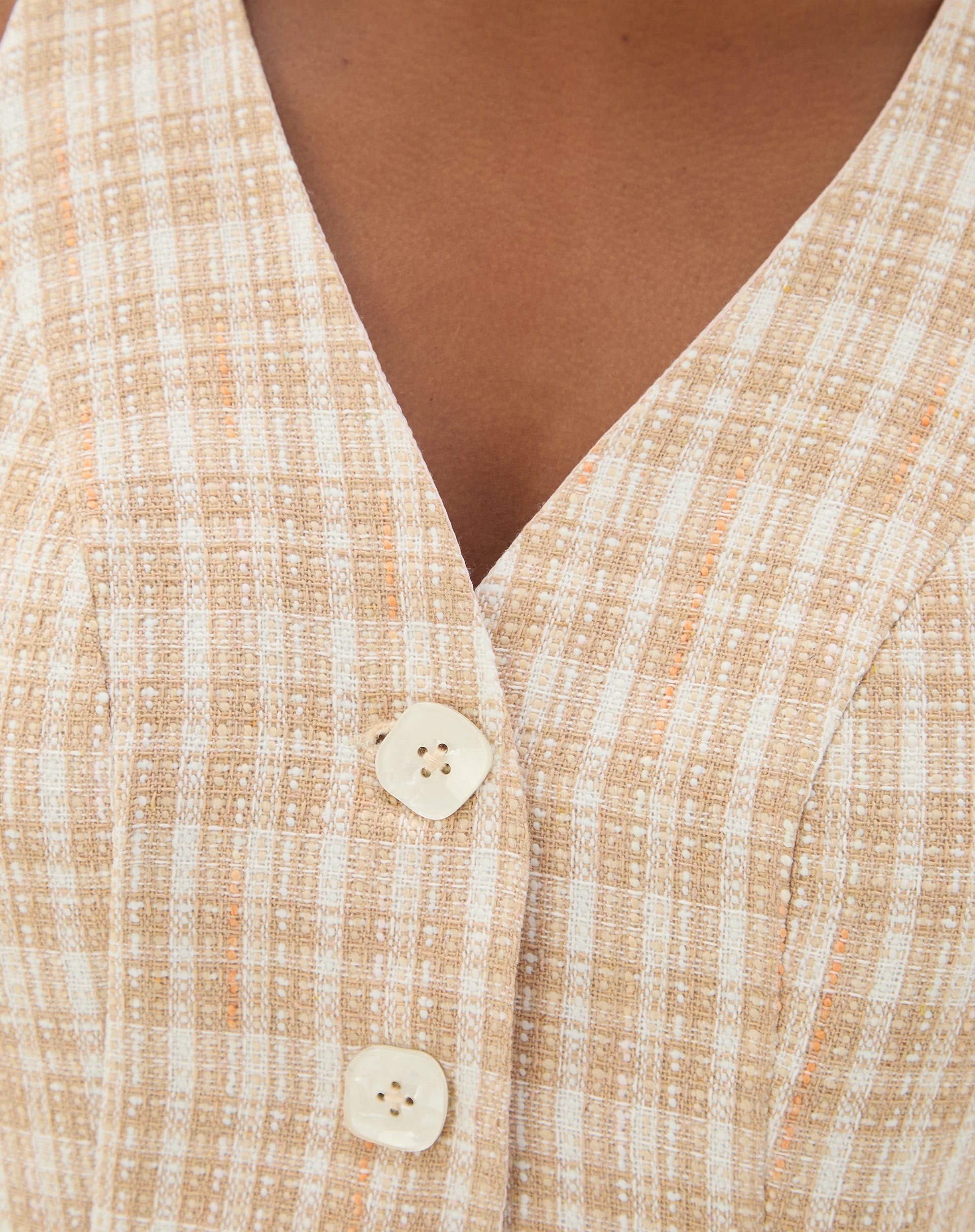 Close-up dos botões do colete de alfaiataria com estampa xadrez.