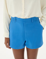 Close-up do shorts curto reto de alfaiataria azul mostrando detalhes do cós e bolsos.