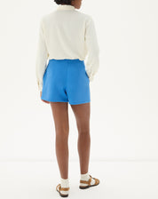 Vista traseira do shorts curto reto de alfaiataria azul mostrando o ajuste perfeito.