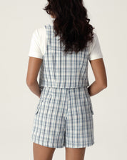 Detalhe do shorts frente transpassada de alfaiataria com estampa xadrez, evidenciando o acabamento e os bolsos.