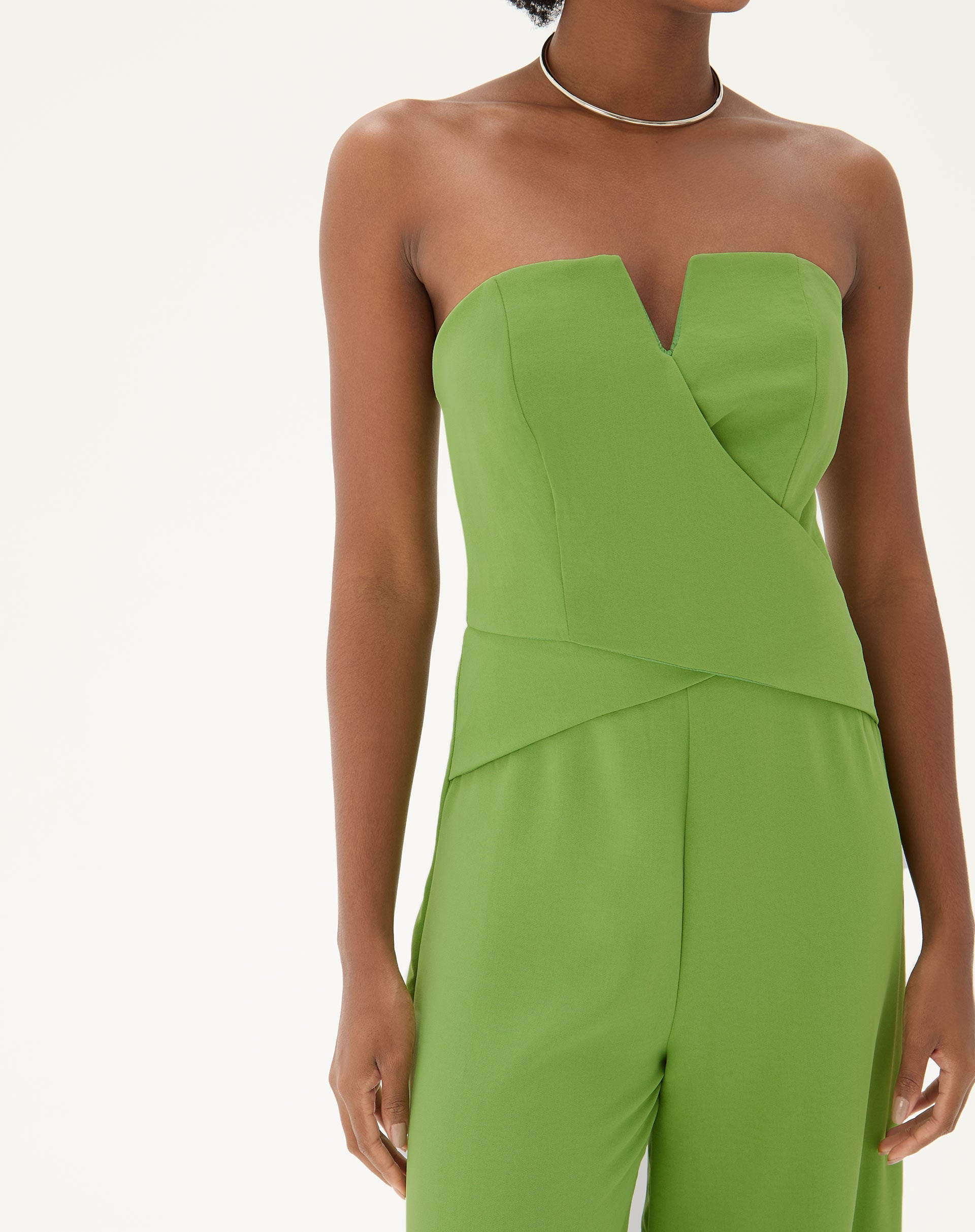 Imagem de um macacão sem alças de alfaiataria em verde, visto de costas, mostrando o fechamento em zíper.