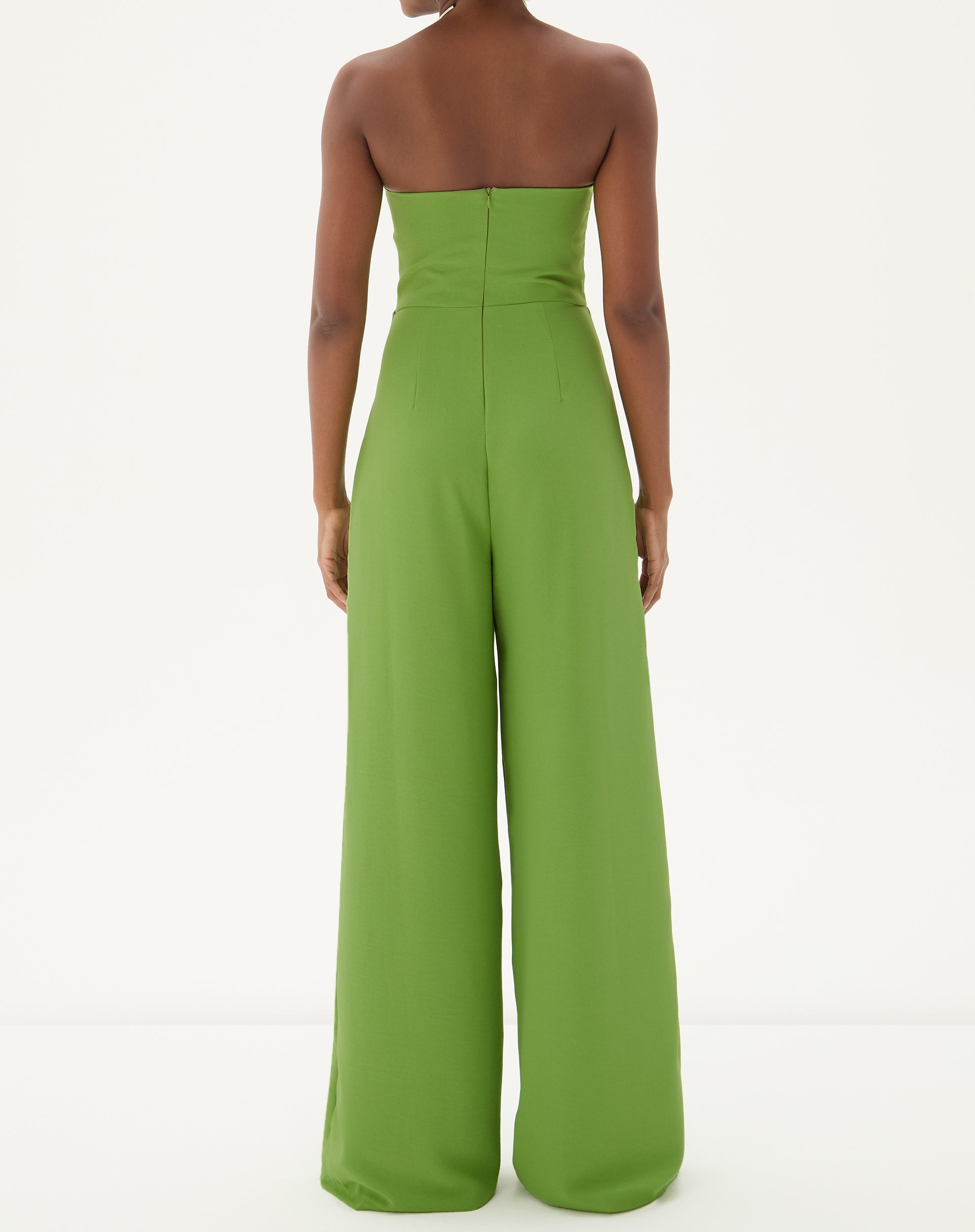 Close-up do decote reto do macacão sem alças de alfaiataria em verde, evidenciando o acabamento impecável.