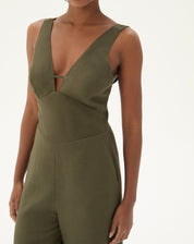 Close-up do macacão verde mostrando o decote em V e detalhes minimalistas.