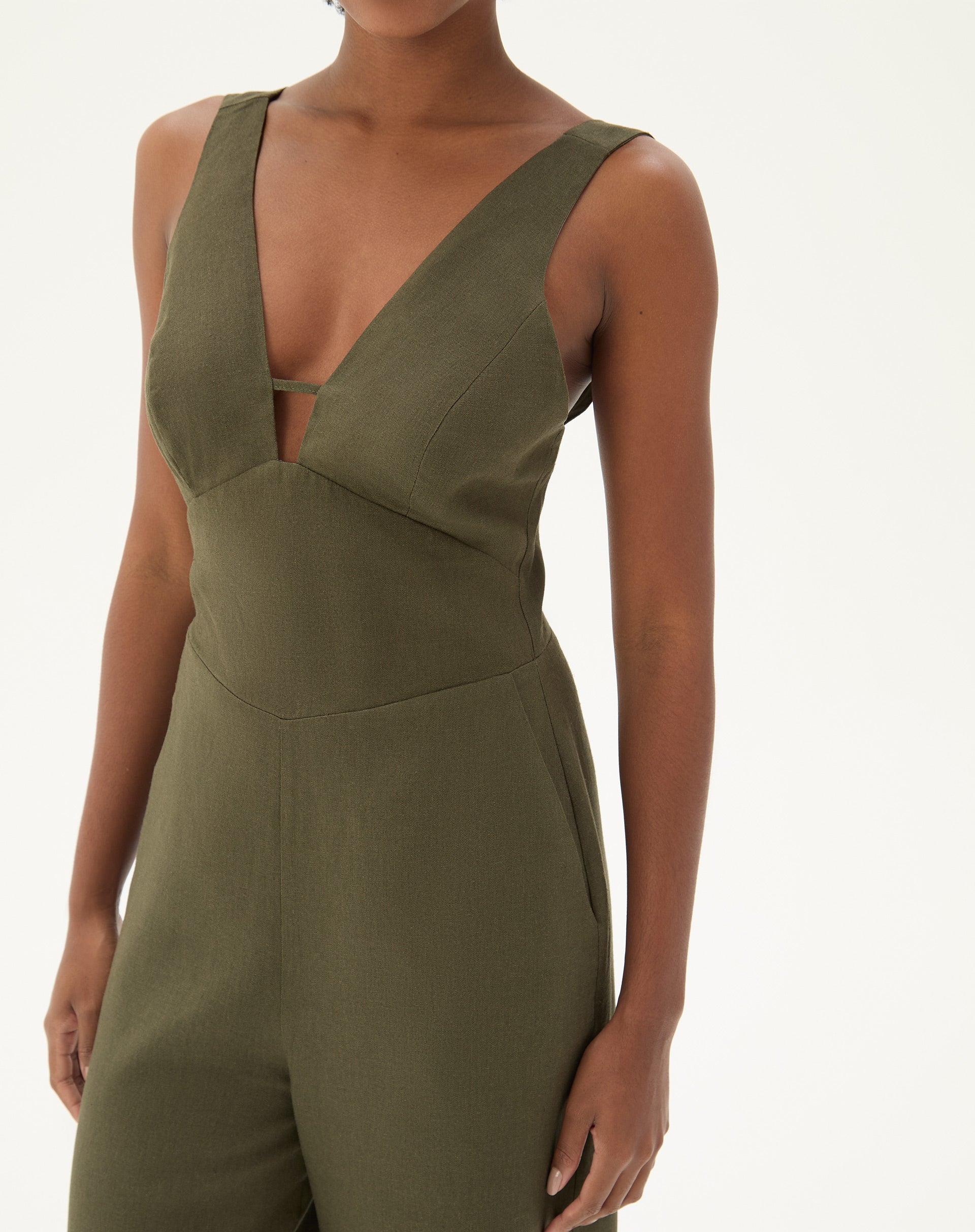 Close-up do macacão verde mostrando o decote em V e detalhes minimalistas.