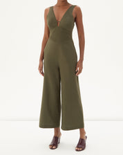 Vista frontal do macacão verde com design de alfaiataria e pernas largas.