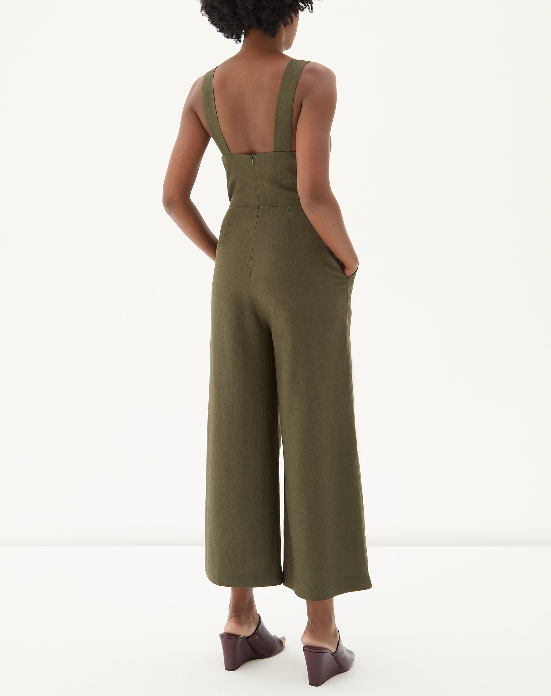 Vista traseira do macacão verde destacando o fechamento e bolsos laterais.