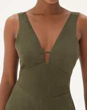 Detalhe do decote em V do macacão verde com alças largas.