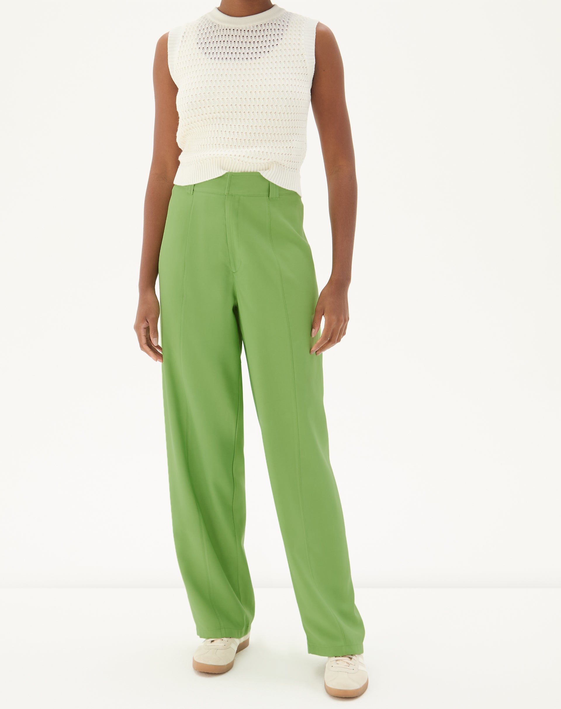 Modelo vestindo calça reta verde com bolsos de alfaiataria, vista frontal.