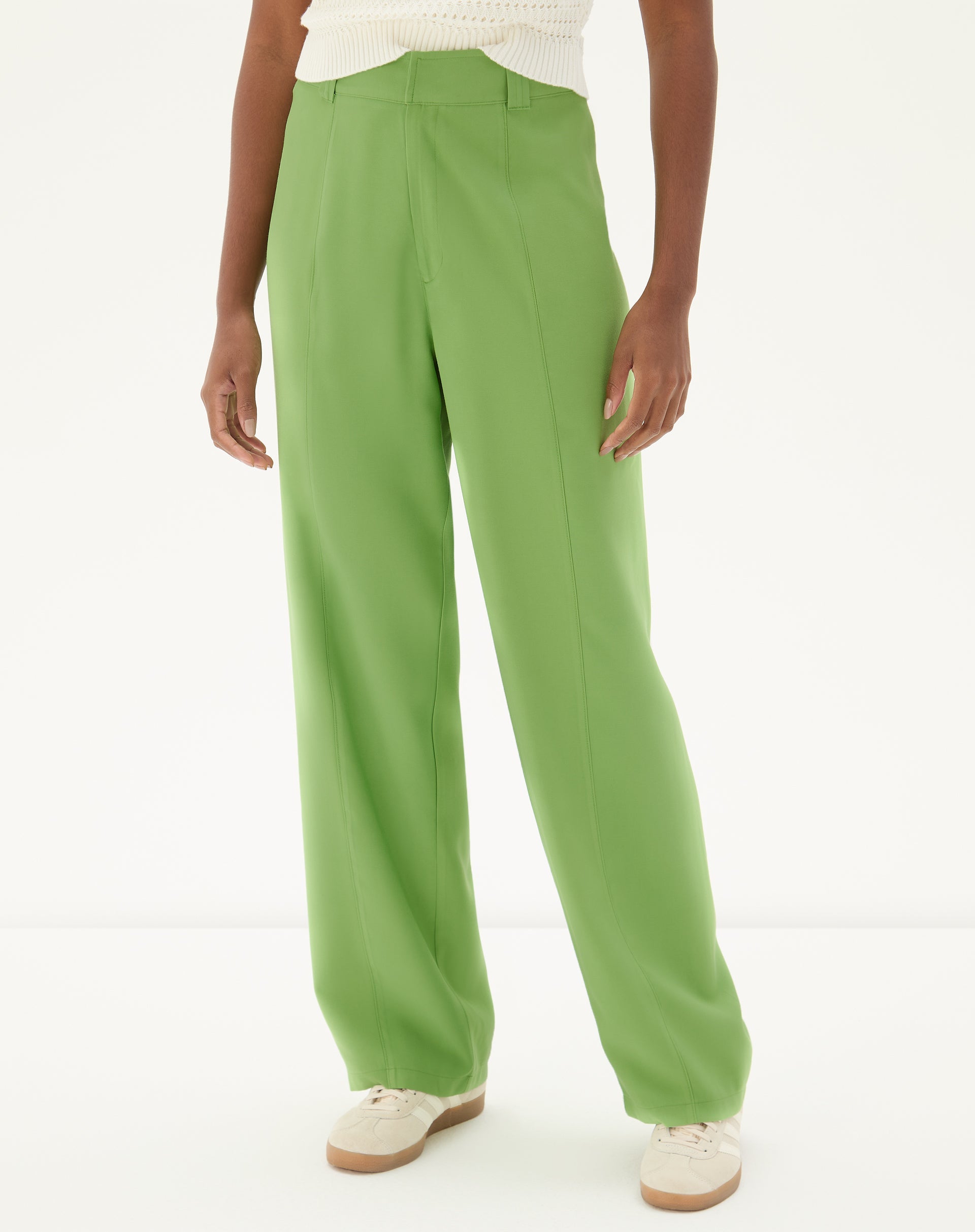 Modelo vestindo calça reta verde com bolsos de alfaiataria, vista lateral.