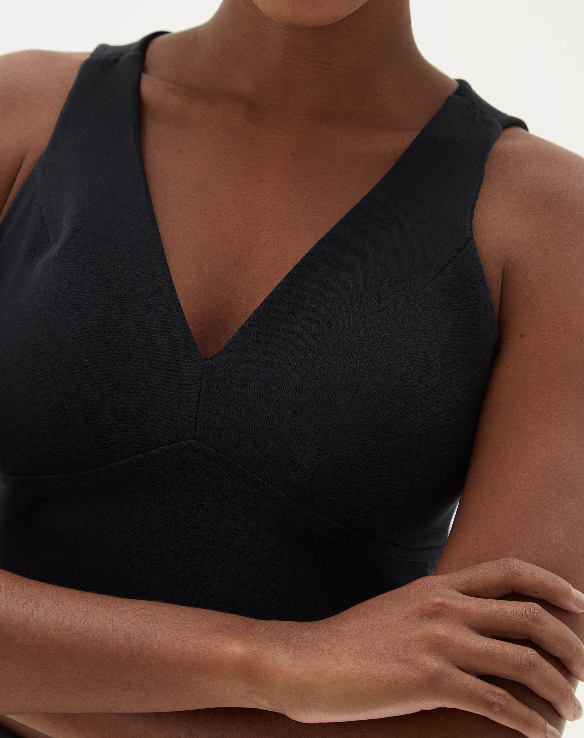 Detalhe do decote V da blusa preta, mostrando o acabamento refinado.