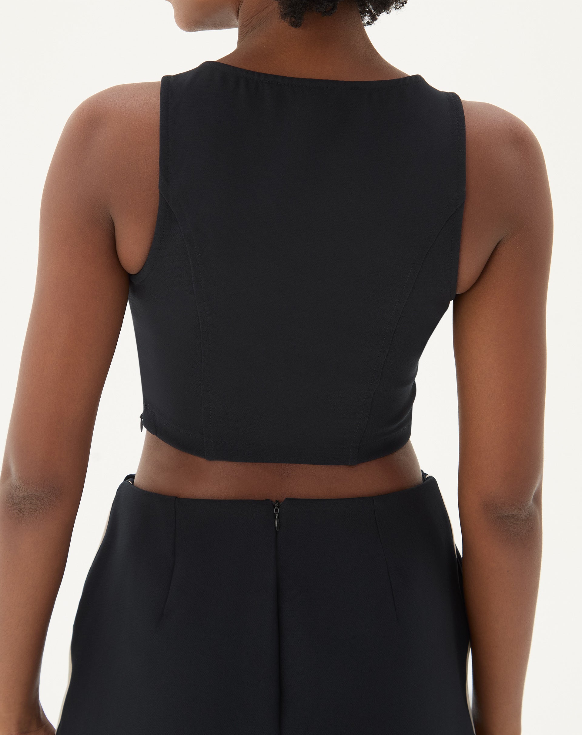 Vista traseira da blusa preta, destacando o fechamento com zíper.