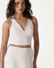 Blusa decote V alfaiataria bege vista de frente, destacando o design minimalista e o tecido fluido.