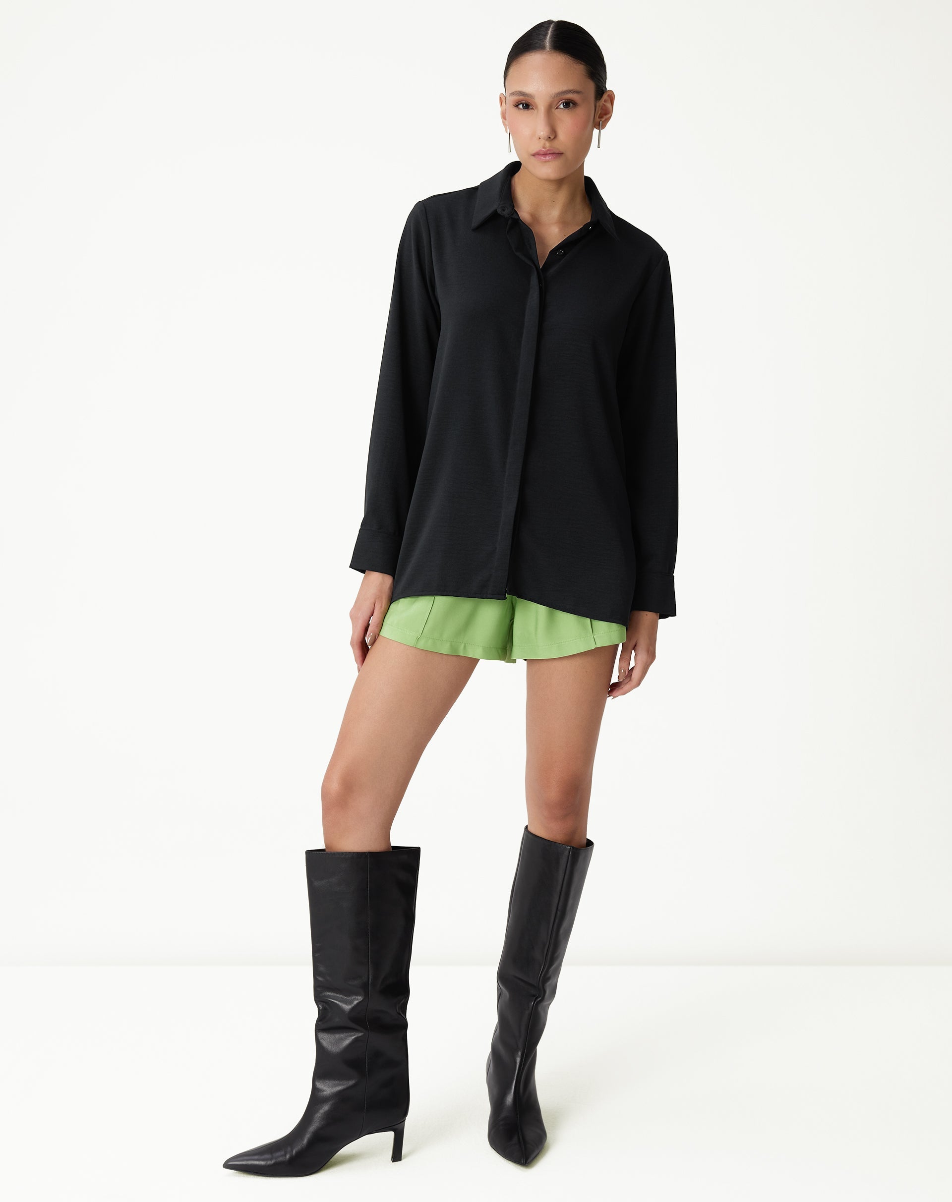 Vista completa da camisa preta de manga longa com barra reta, combinada com shorts verdes.