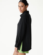 Vista lateral da camisa preta de manga longa com barra reta, destacando o tecido.