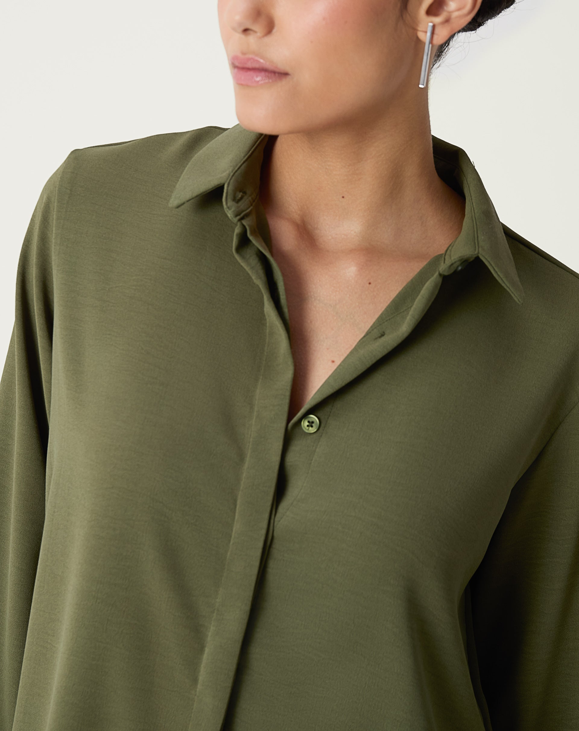 Detalhe do colarinho pontudo da camisa verde.