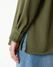 Detalhe do punho simples com botão da camisa verde.