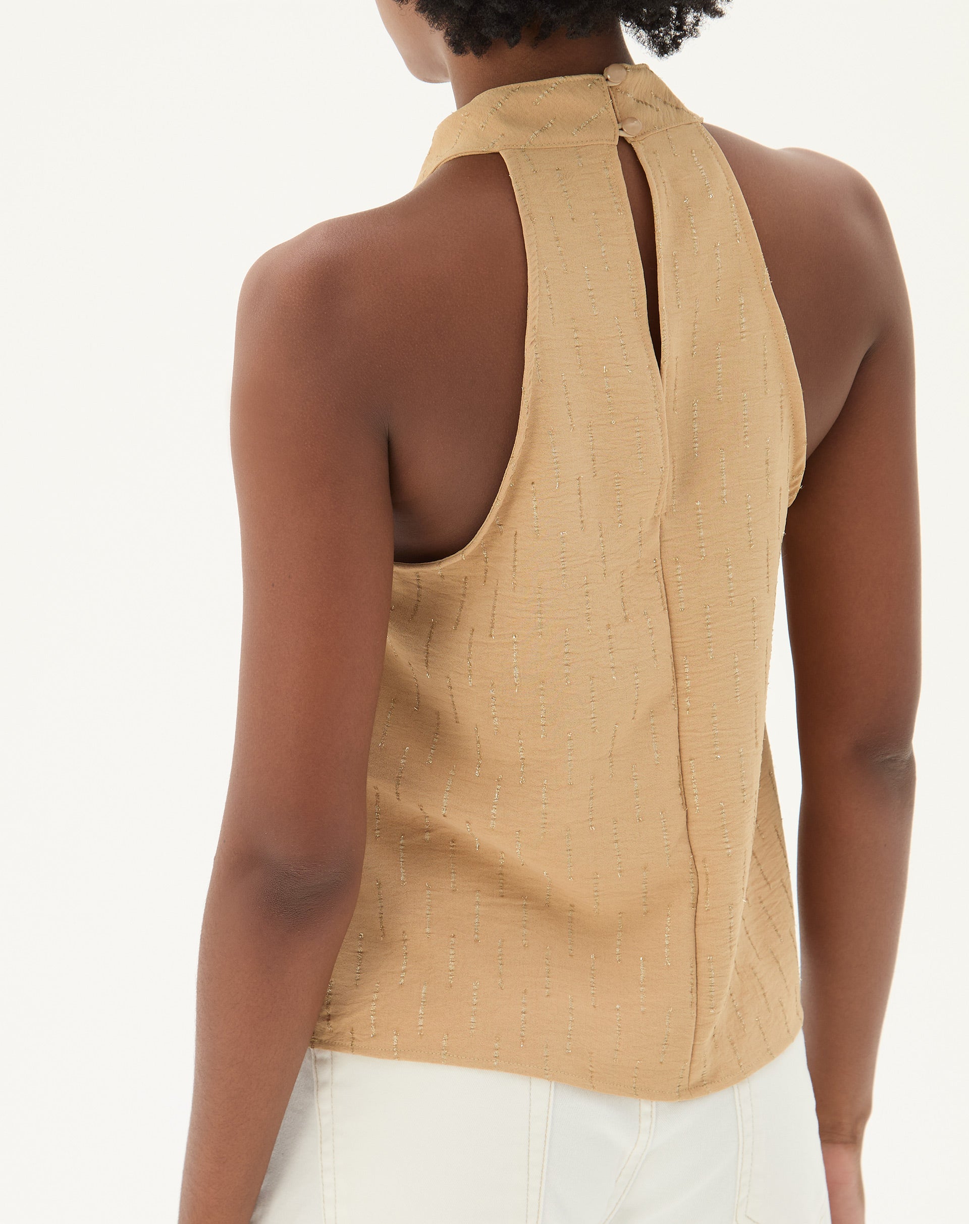 Vista traseira da blusa frente única areia, destacando o fechamento.