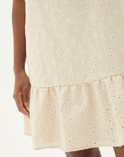 Detalhe do bordado floral no tecido bege do vestido curto.