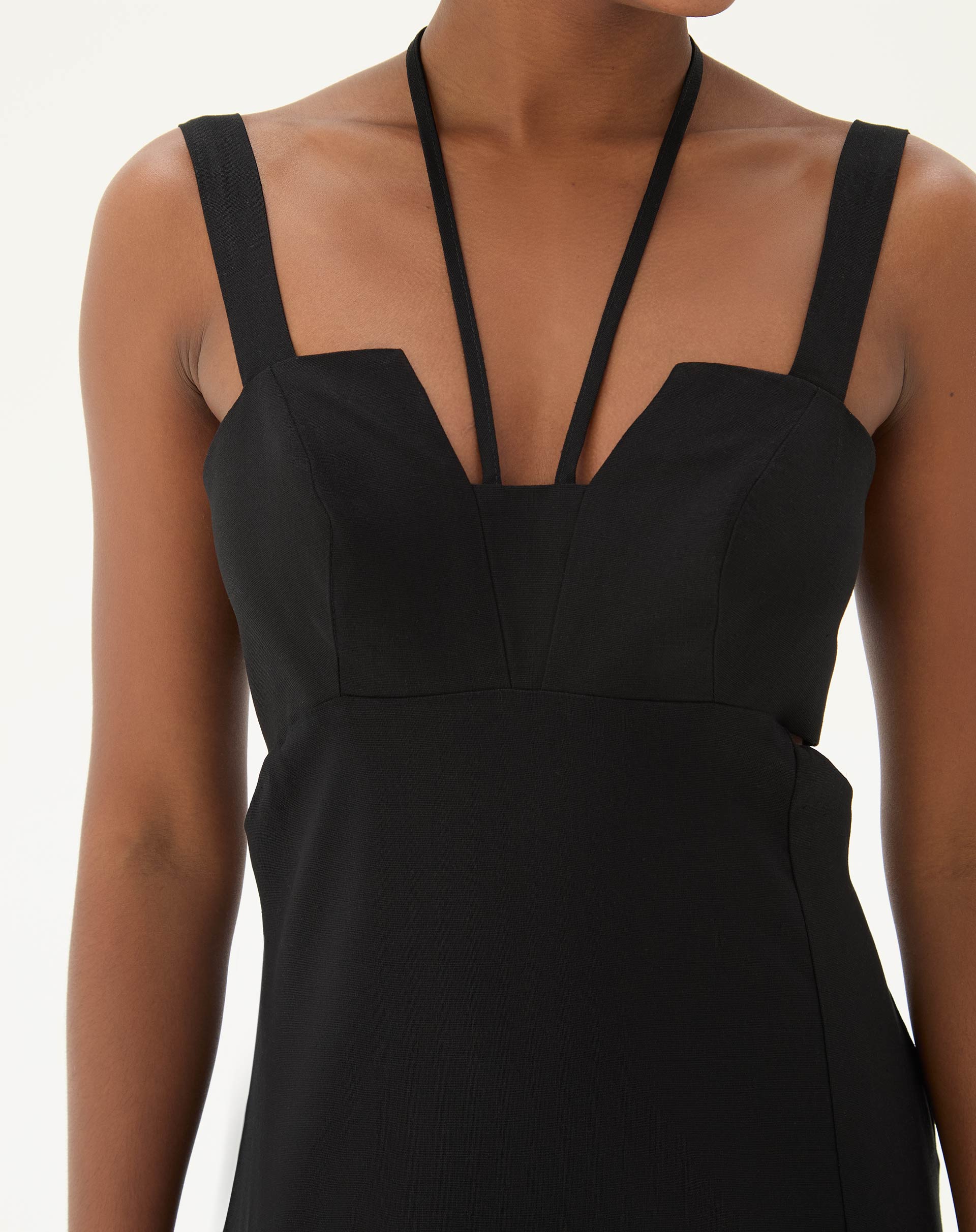 Detalhe do decote reto e alças finas do vestido preto.