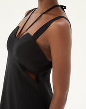 Close-up do detalhe lateral do vestido preto mostrando o tecido e acabamento.