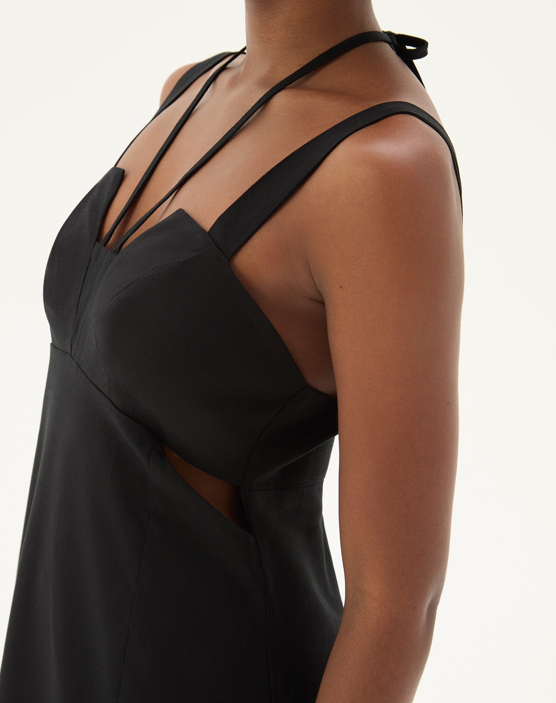 Close-up do detalhe lateral do vestido preto mostrando o tecido e acabamento.