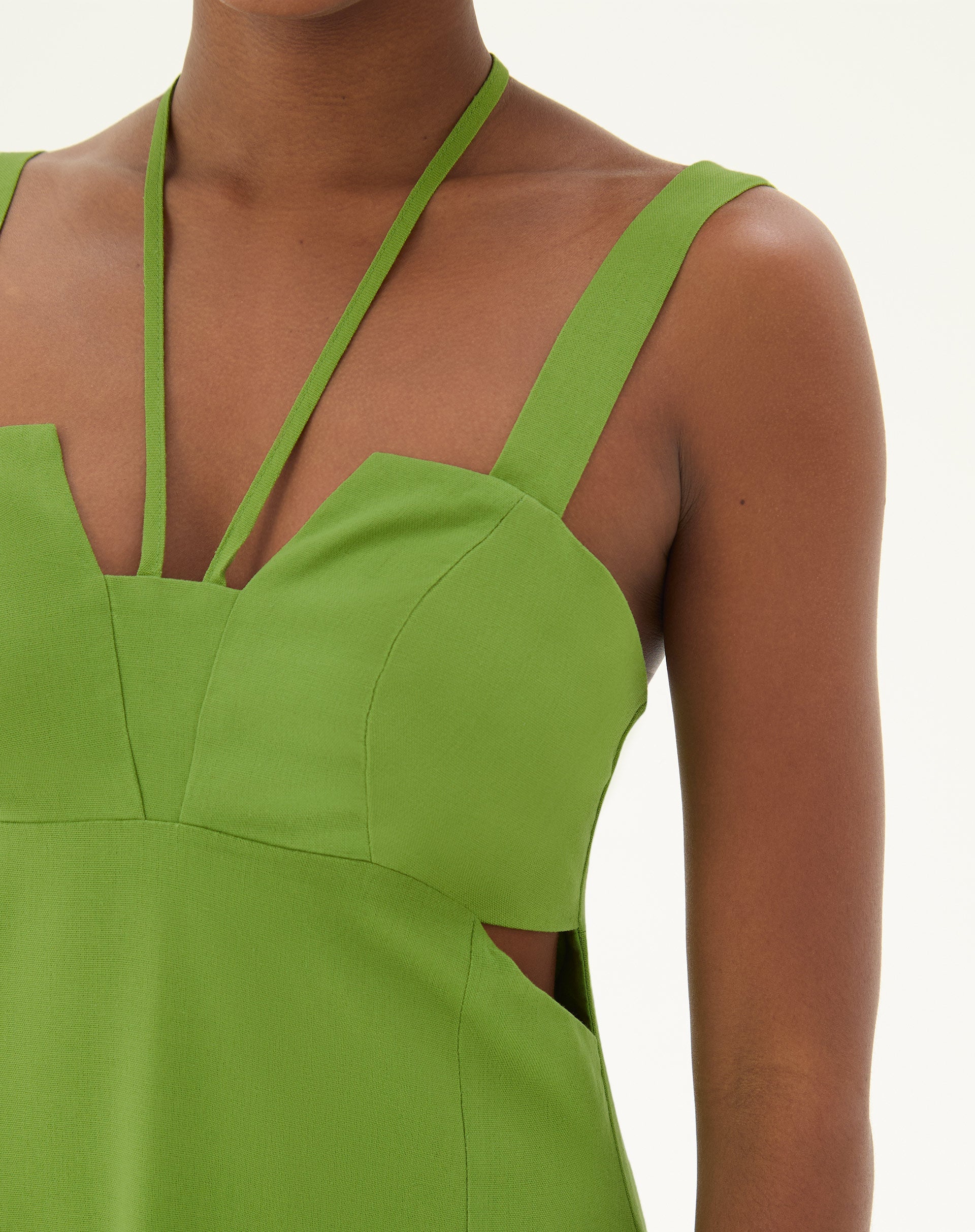 Close-up do decote reto e alças finas do vestido verde.