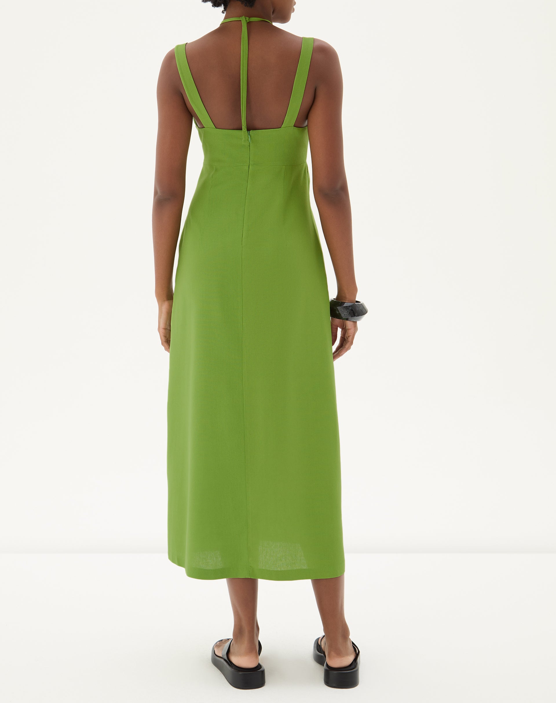 Vista traseira do vestido verde mostrando o design das alças e comprimento midi.