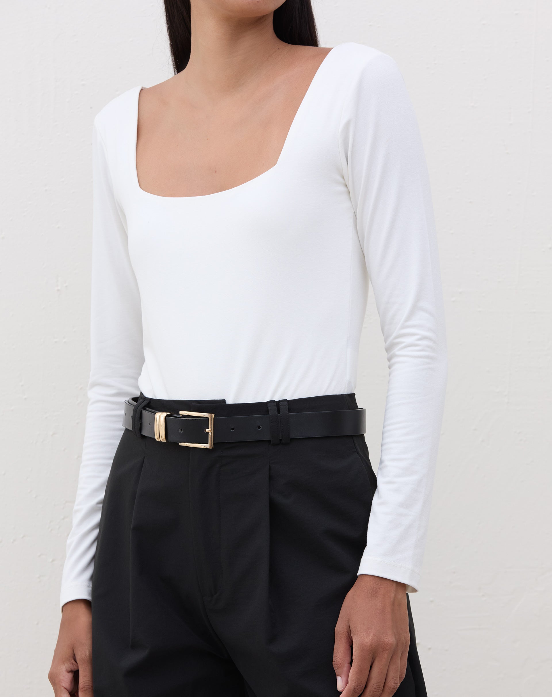 Body manga longa com decote quadrado em off-white, visto de frente, combinado com calça preta.