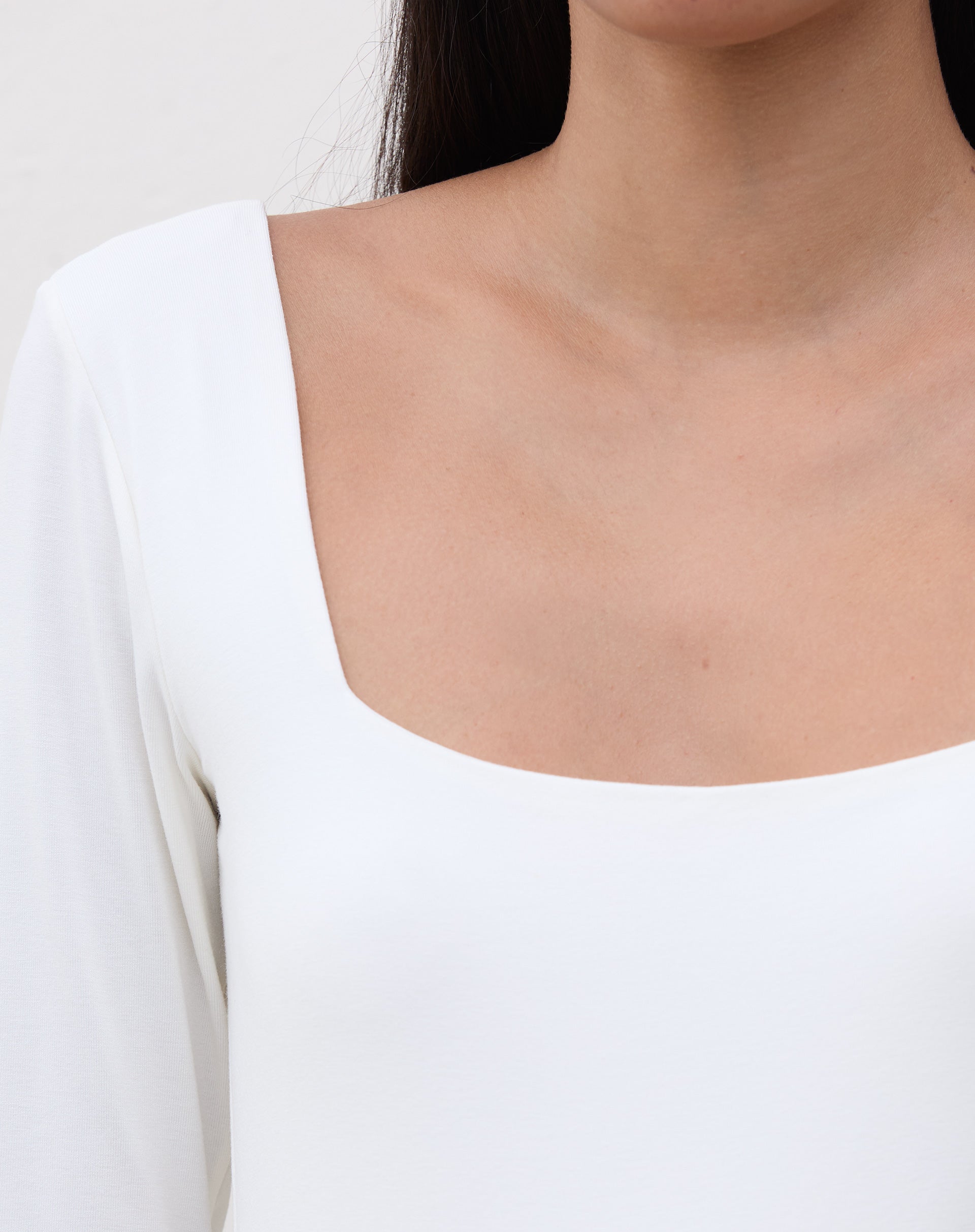 Detalhe do decote quadrado do body em off-white.