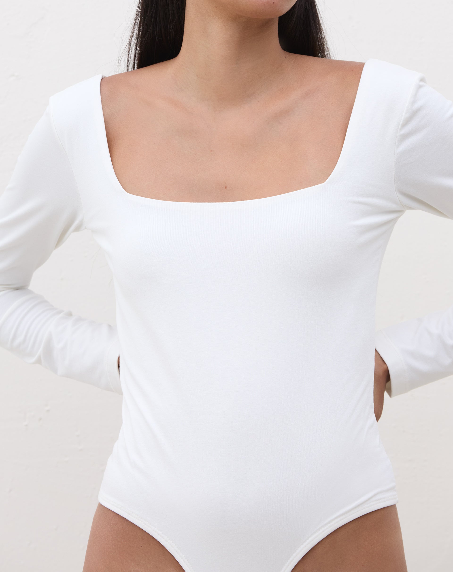 Vista lateral do body manga longa em off-white.