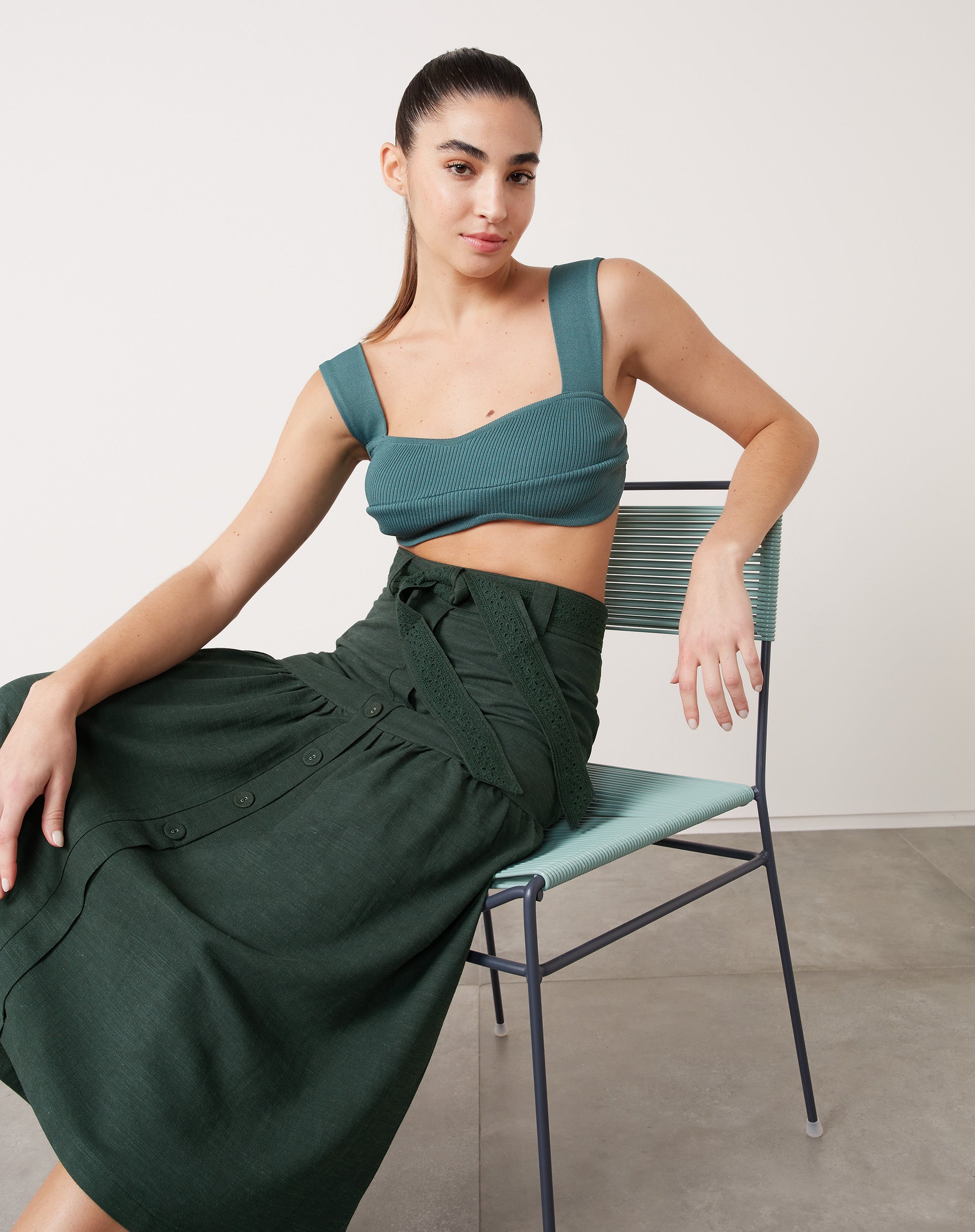 Top curto de tricô verde escuro com alças largas, combinado com saia midi.