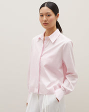 Camisa básica curta em rosa claro, vista de frente com detalhes da gola e mangas.