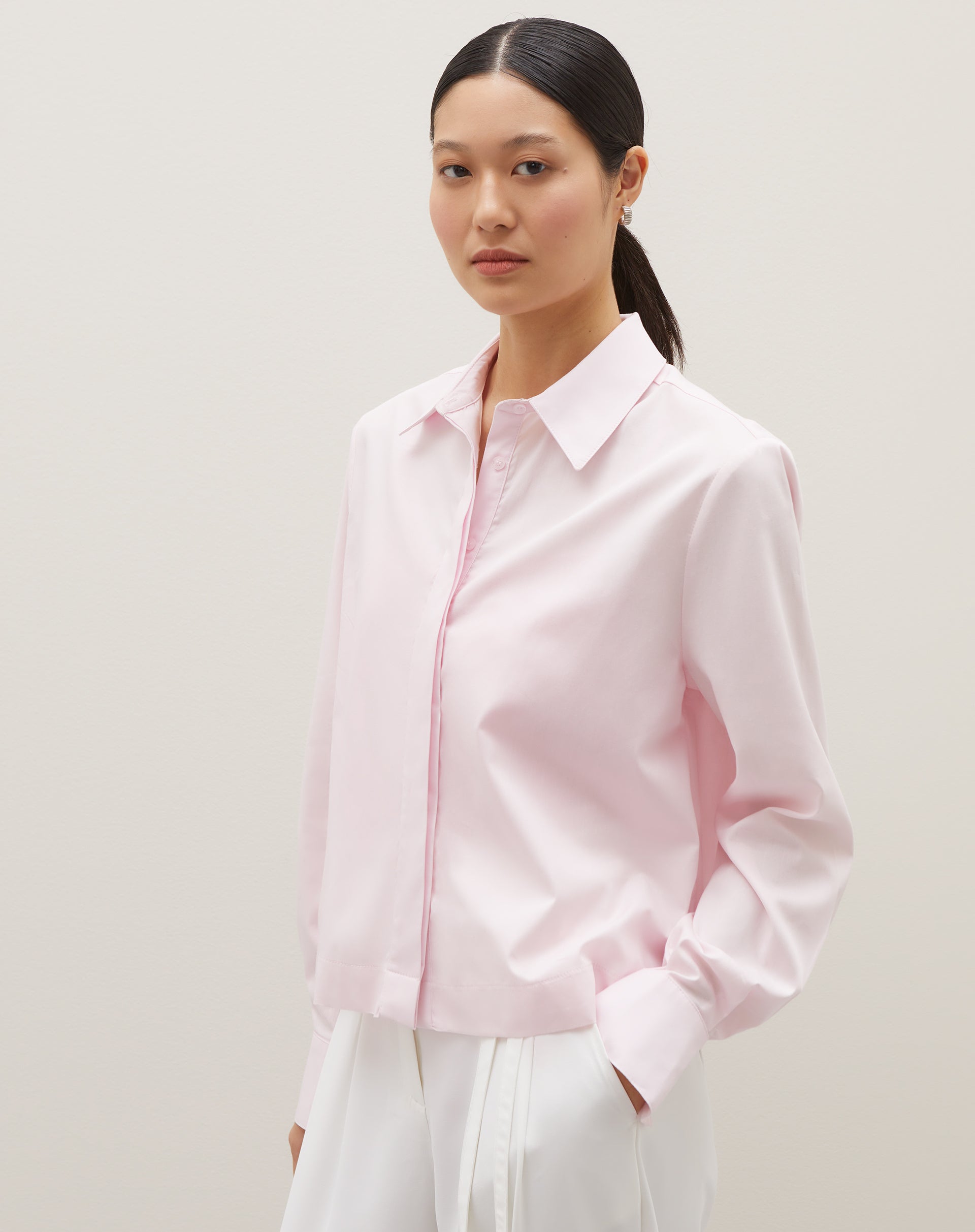 Camisa básica curta em rosa claro, vista de frente com detalhes da gola e mangas.