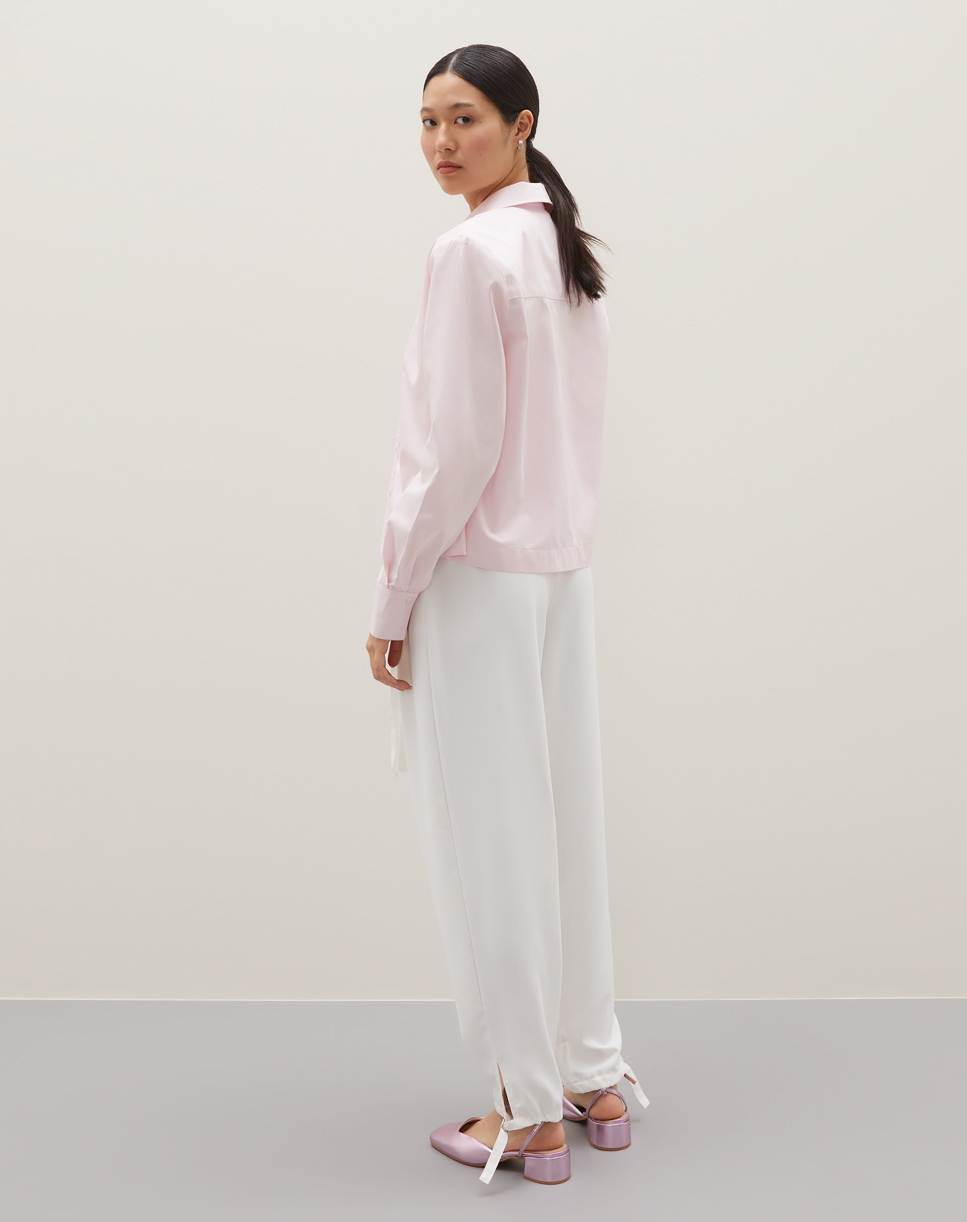 Camisa básica curta em rosa claro, vista de lado mostrando o caimento.