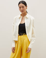 Camisa básica curta em amarelo claro, vista frontal com mangas longas e gola clássica.