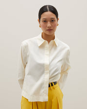 Camisa básica curta em amarelo claro, detalhe frontal com fechamento de botões.