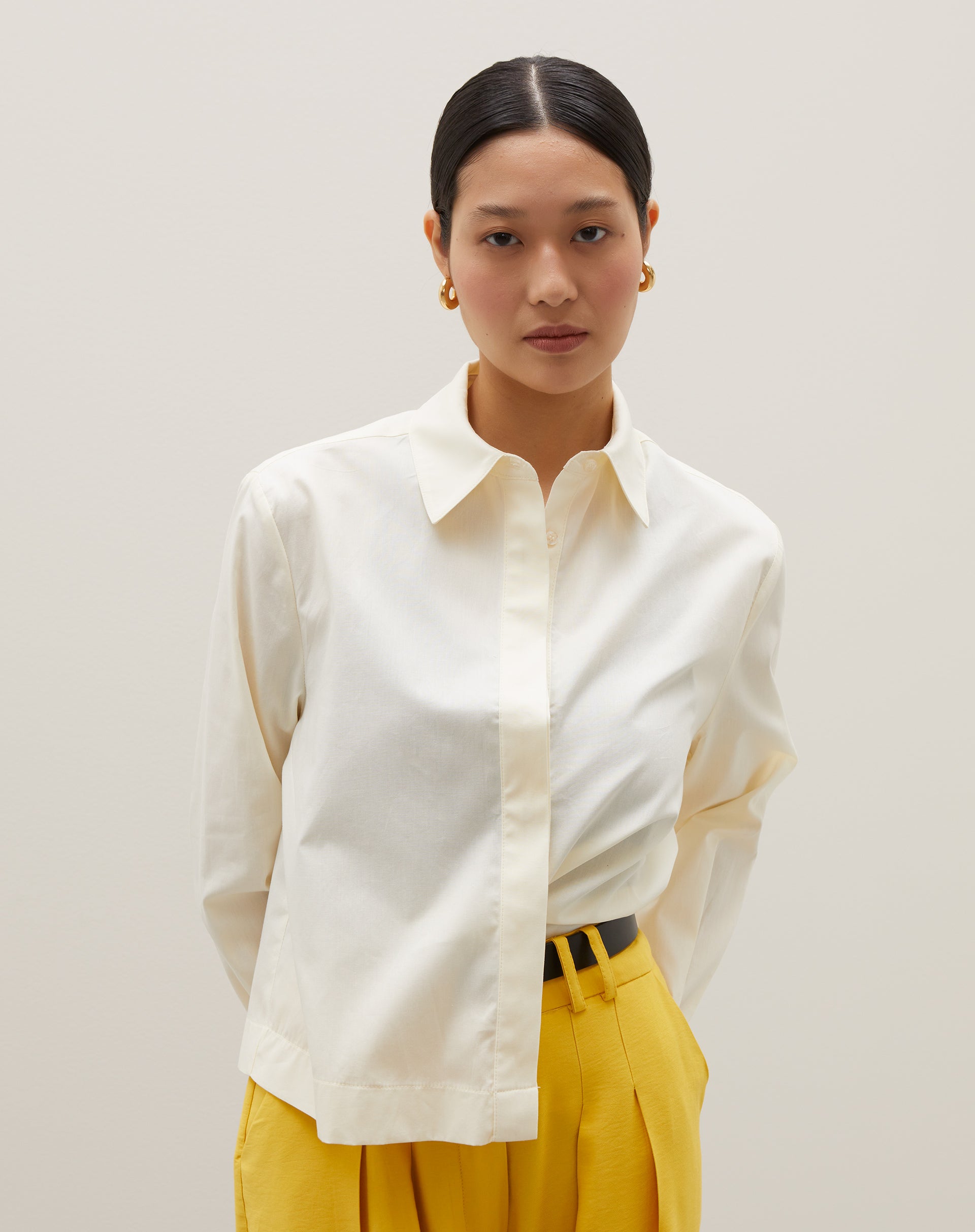 Camisa básica curta em amarelo claro, detalhe frontal com fechamento de botões.