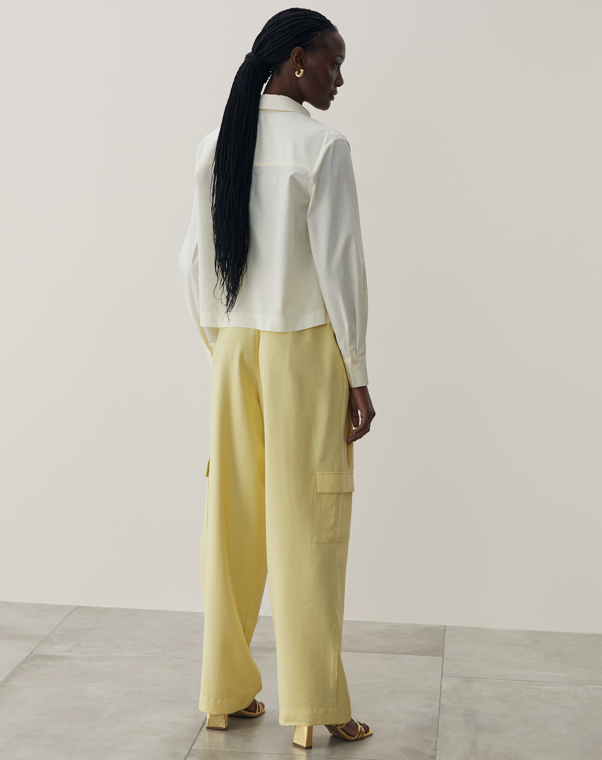 Vista traseira da camisa básica curta em amarelo claro, mostrando o design simples.