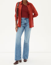 Modelo vestindo calça jeans flare azul claro com camisa vermelha.