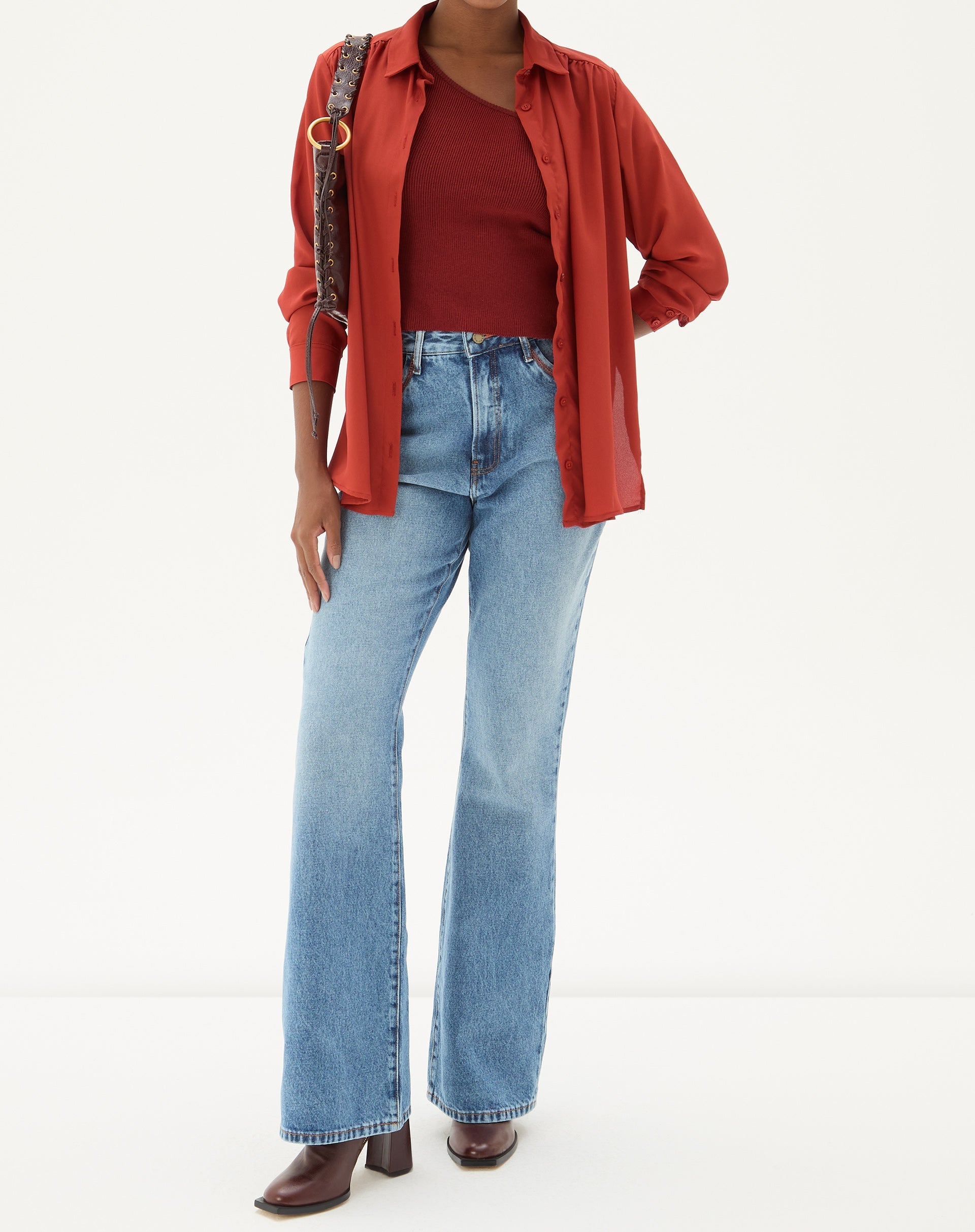 Modelo vestindo calça jeans flare azul claro com camisa vermelha.