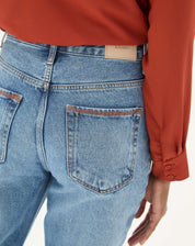 Detalhe do bolso traseiro da calça jeans azul claro.