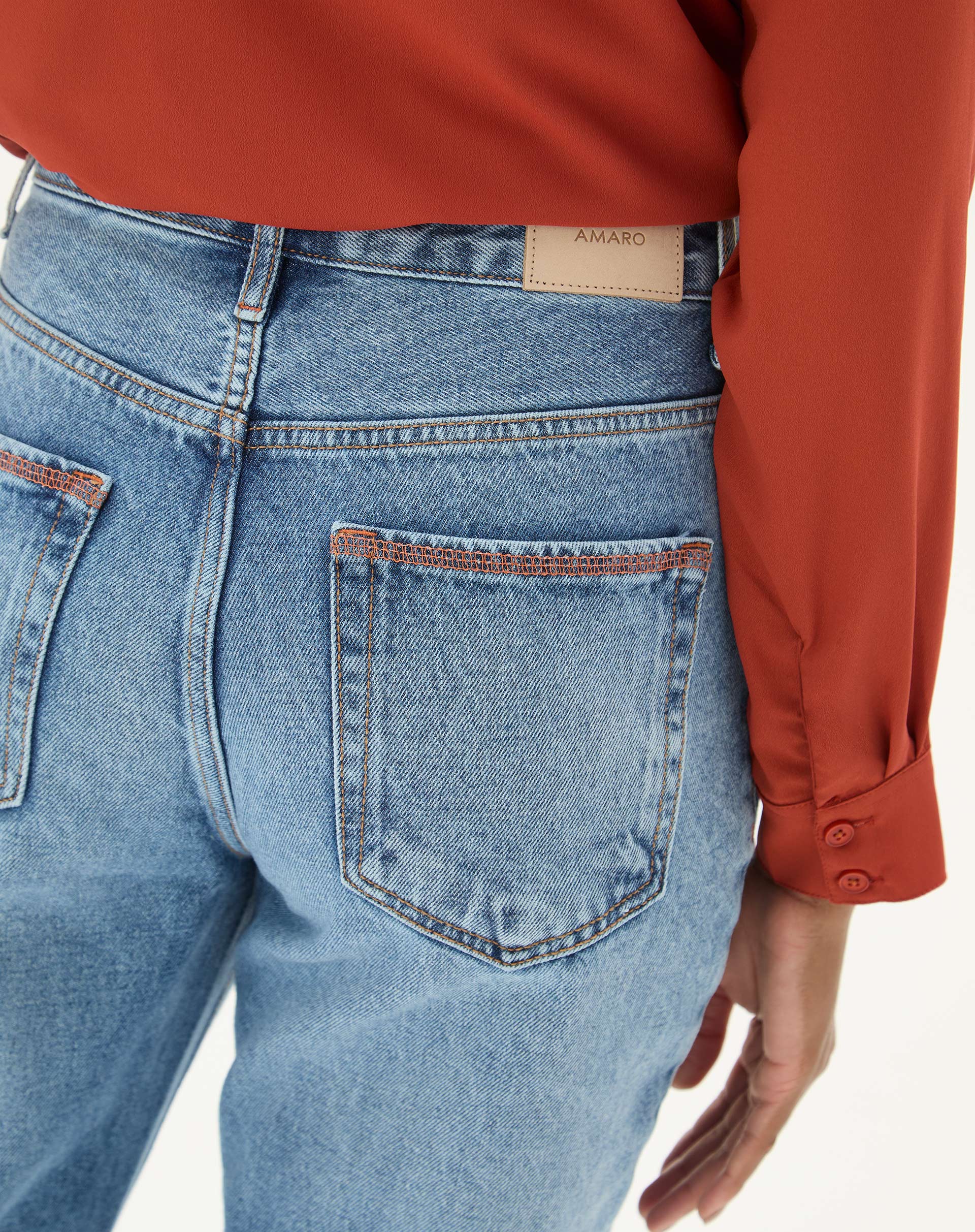 Detalhe do bolso traseiro da calça jeans azul claro.