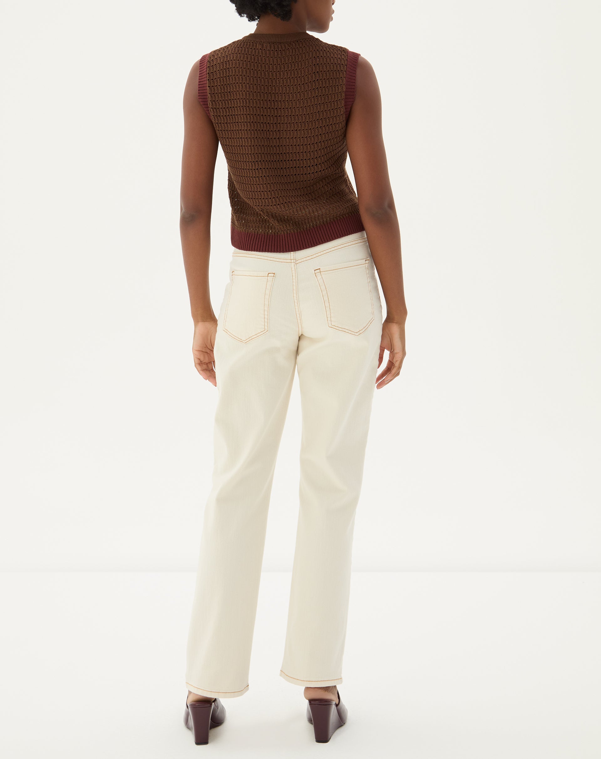 Close-up da cintura alta e detalhes de costura da calça reta em sarja bege.