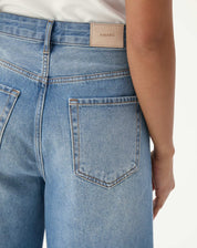 Close-up da parte traseira da bermuda jeans alongada evasê mostrando bolsos e etiqueta.