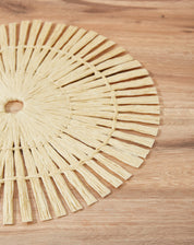 Close-up de um lugar americano redondo em papel, destacando o entrelaçamento das tiras em cor bege.